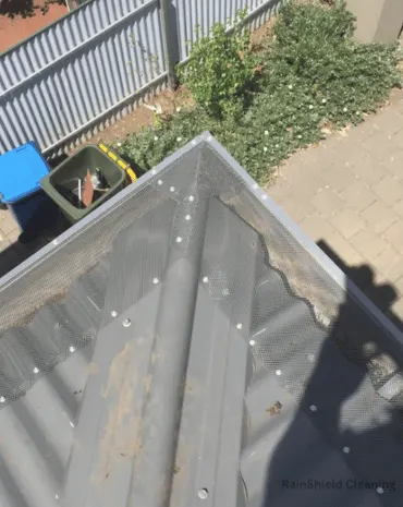 A clean and well-maintained gutter along the corner of a tin shed, free of debris and blockages.
