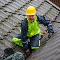 A professional gutter cleaner works happily on a residential roof, delivering the best gutter cleaning service in Cincinnati, Ohio.